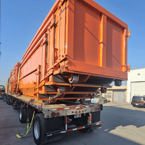 Heavy-duty dumpster manufacturing facility with steel frames being welded.